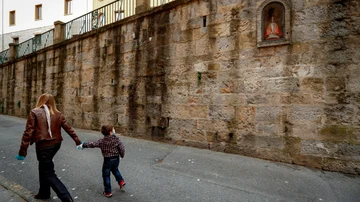 Una mujer y un niño pasan por delante de la hornacina de San Fermín en la cuesta de Santo Domingo de Pamplona
