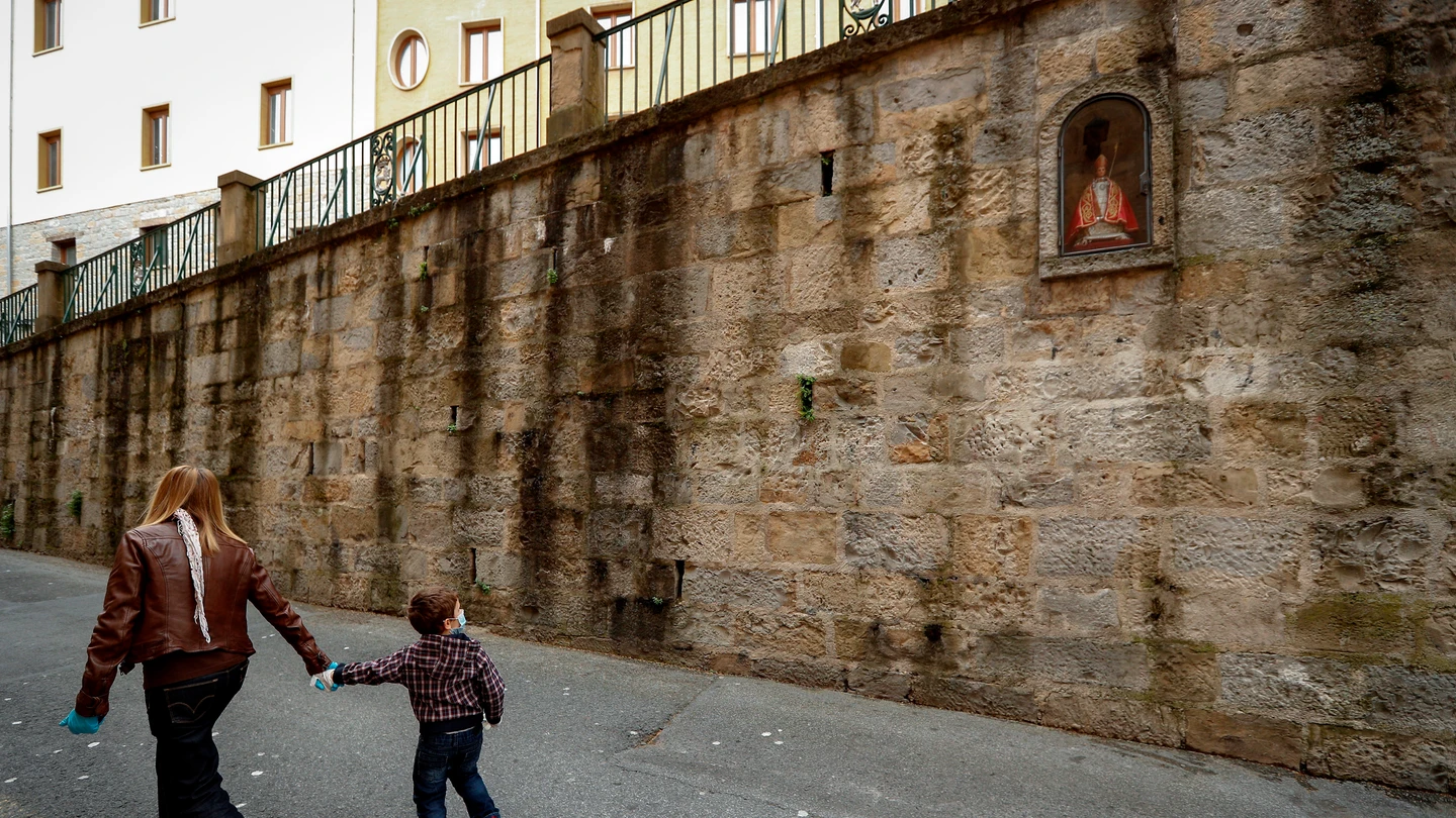 Una mujer y un niño pasan por delante de la hornacina de San Fermín en la cuesta de Santo Domingo de Pamplona coronavirus
