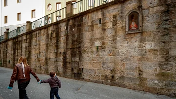 Una mujer y un niño pasan por delante de la hornacina de San Fermín en la cuesta de Santo Domingo de Pamplona