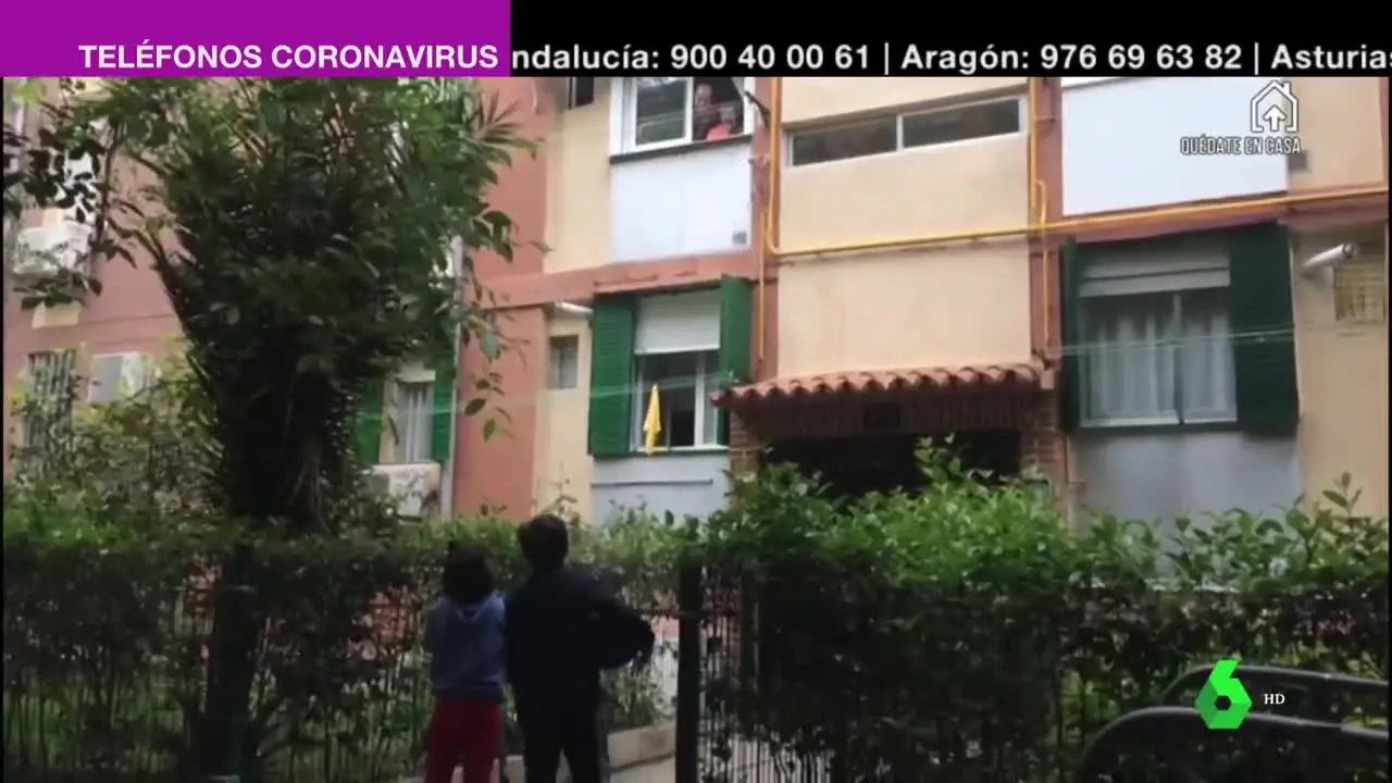 Unos niños saludan desde la calle a sus abuelos, que cumplen con el confinamiento