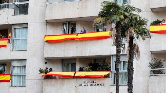 Edificio de la Glorieta de las Cigarreras, en Sevilla, repleto de banderas de Espa&ntilde;a con crespones negros