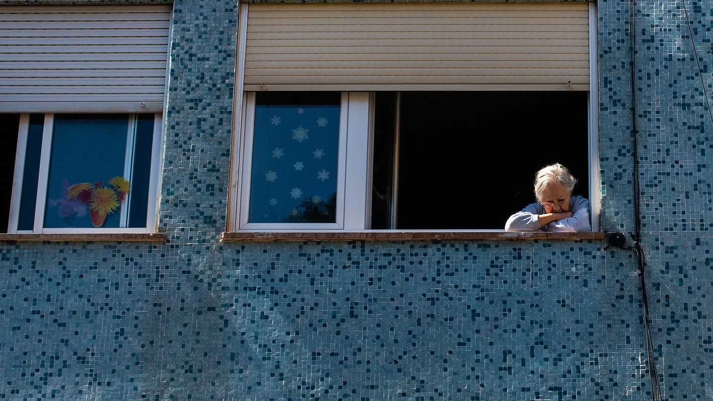 Una mujer mira a la calle por la ventana de su casa, en Barcelona Una mujer mira a la calle por la ventana de su casa, en Barcelona