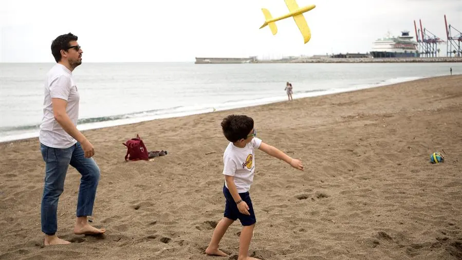 Un niño juega con su padre en la playa de la Malagueta tras 43 días de confinamiento