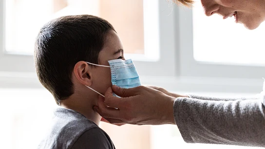 Una mujer coloca una mascarilla a un niño Una mujer coloca una mascarilla a un niño