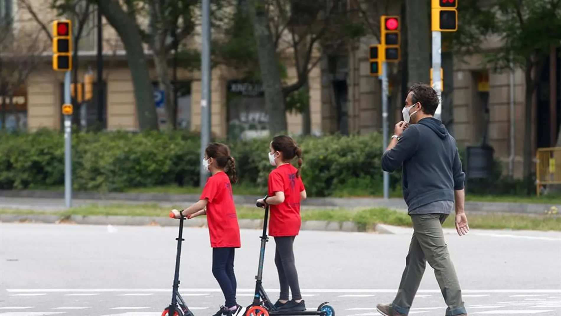 Un hombre y sus dos hijas caminan por una calle de Barcelona