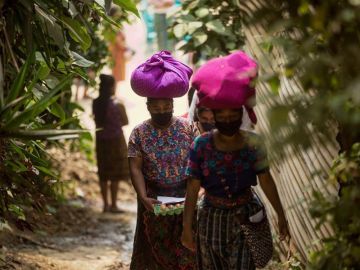 Mujeres con mascarilla portan alimentos entregados como ayuda alimentaria en Guatemala Mujeres con mascarilla portan alimentos entregados como ayuda alimentaria en Guatemala