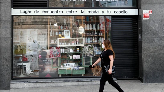 Una mujer pasea ante una peluquería durante la crisis del coronavirus Una mujer pasea ante una peluquería durante la crisis del coronavirus