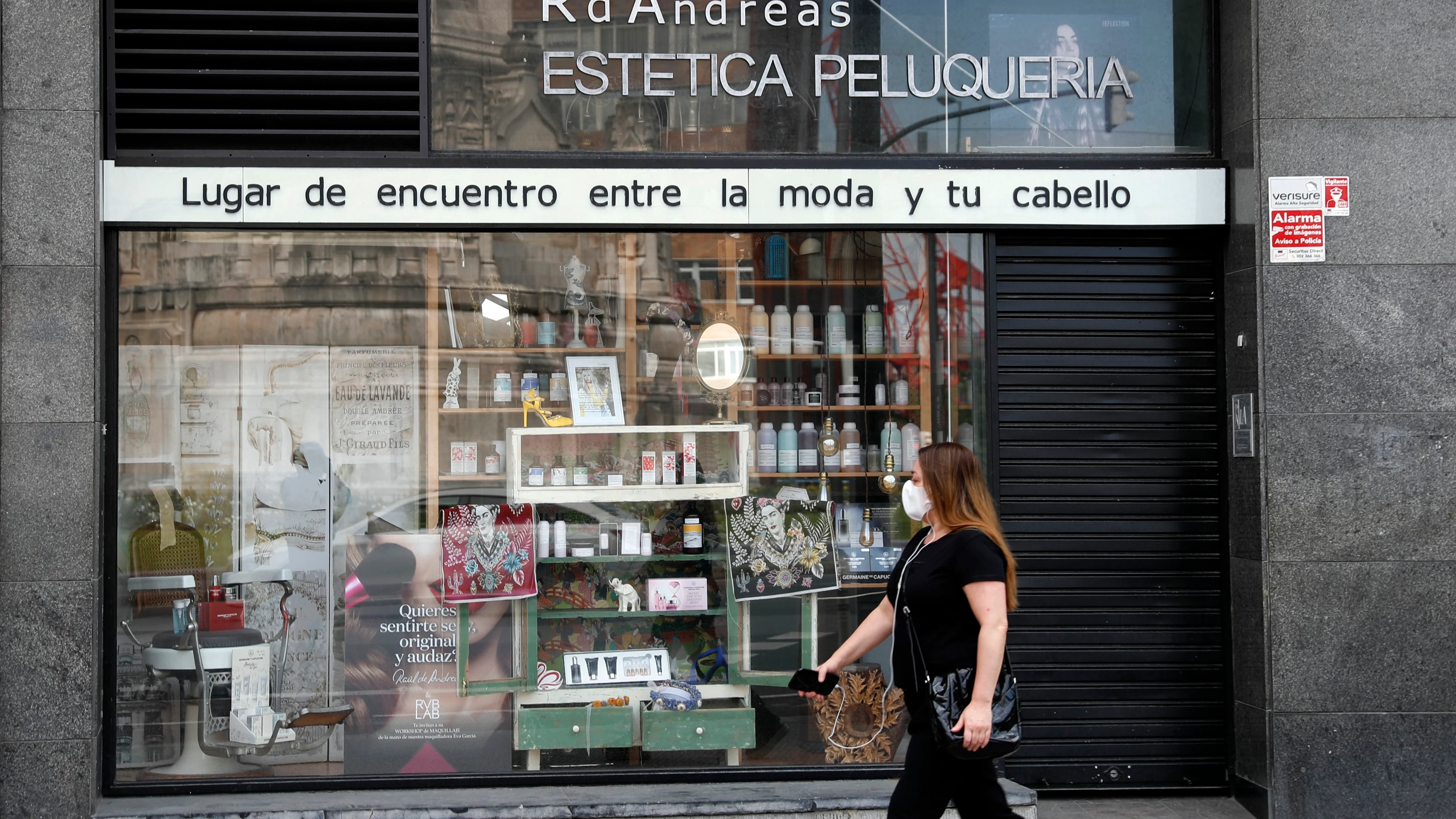 Una mujer pasea ante una peluquería durante la crisis del coronavirus