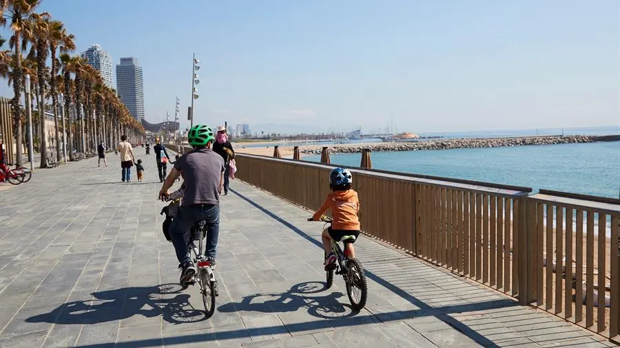 Una familia circula en bici por el paseo marítimo de Barcelona