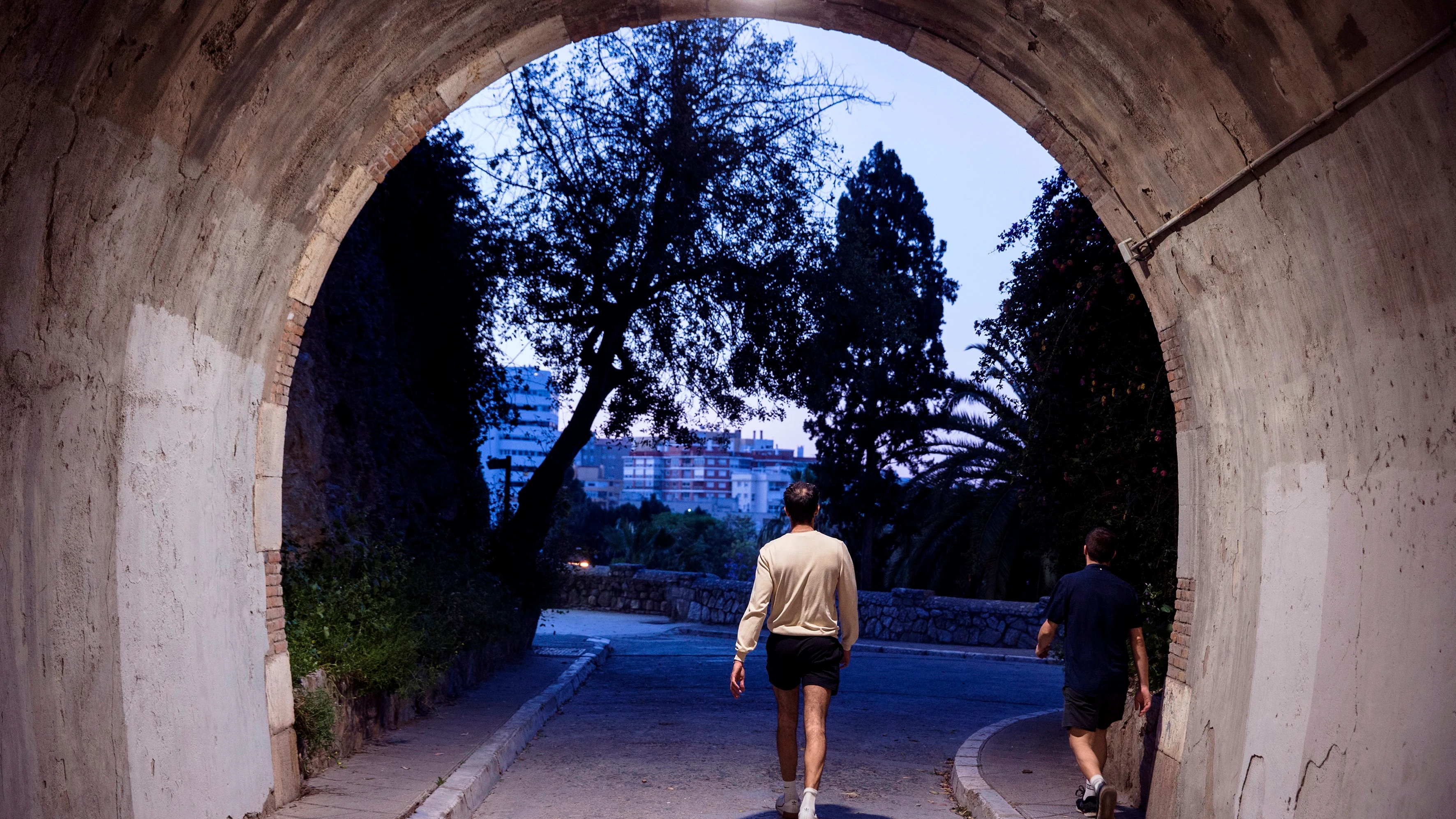 Unas personas pasean a primera hora de la mañana por el centro de Málaga dentro de la nueva normativa que permite hacer actividad en dos franjas horarias