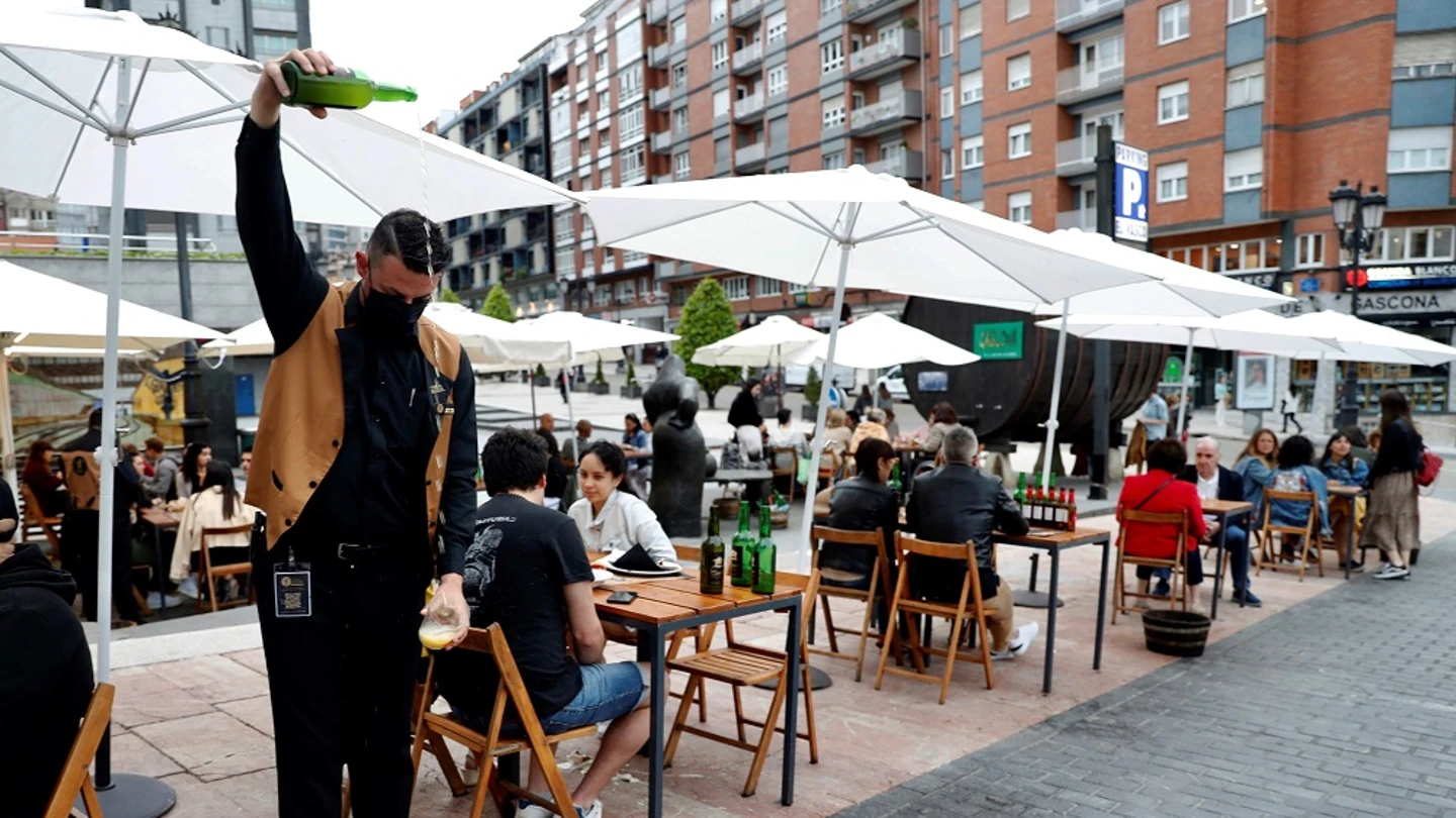 Un camarero escancia sidra en una terraza de Asturias Un camarero escancia sidra en una terraza de Asturias