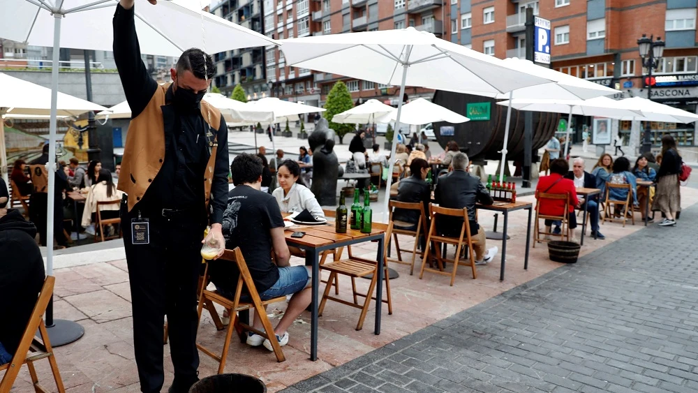 Un camarero escancia sidra en una terraza de Asturias