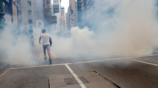 Un hombre huye del lanzamiento de gases lacrimógenos por parte de la Policía en Hong Kong Un hombre huye del lanzamiento de gases lacrimógenos por parte de la Policía en Hong Kong