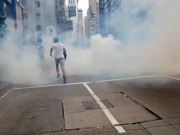 Un hombre huye del lanzamiento de gases lacrimógenos por parte de la Policía en Hong Kong Un hombre huye del lanzamiento de gases lacrimógenos por parte de la Policía en Hong Kong