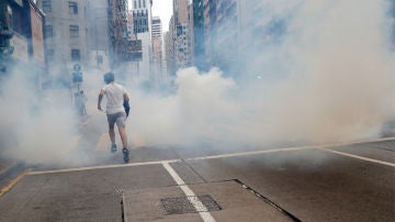 Un hombre huye del lanzamiento de gases lacrimógenos por parte de la Policía en Hong Kong