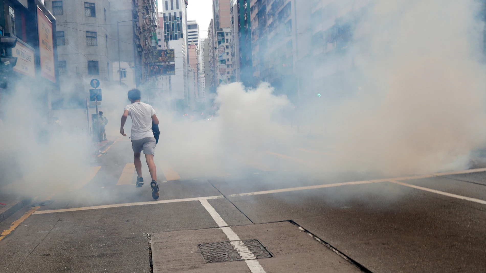 Un hombre huye del lanzamiento de gases lacrimógenos por parte de la Policía en Hong Kong