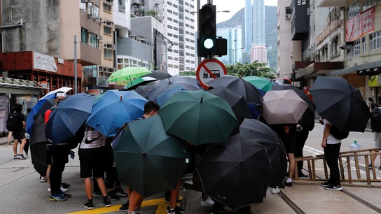 Manifestantes se protegen del lanzamiento de gases lacrimógenos de la Policía en Hong Kong Manifestantes se protegen del lanzamiento de gases lacrimógenos de la Policía en Hong Kong
