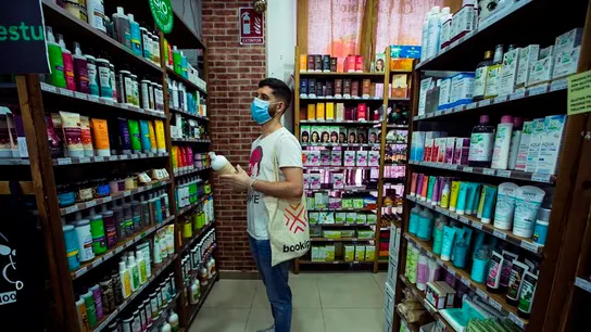 Un hombre frente a una estantería de productos cosméticos. Un hombre frente a una estantería de productos cosméticos.
