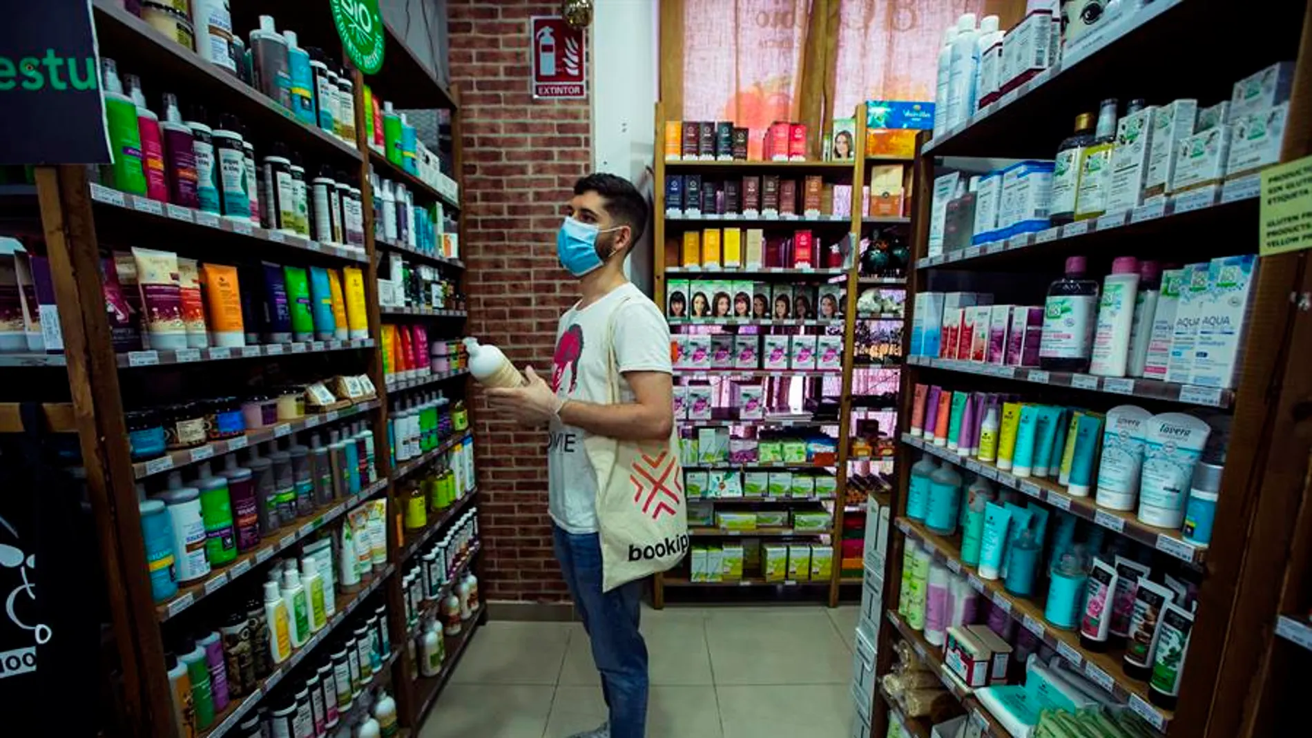 Un hombre frente a una estantería de productos cosméticos.