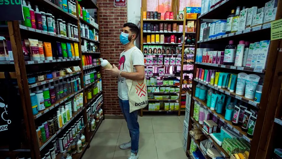 Un hombre frente a una estantería de productos cosméticos.