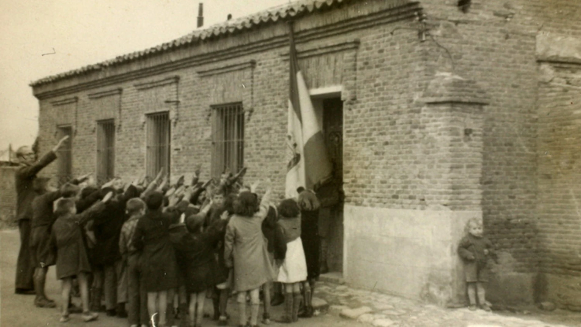 Niños cantando el 'Cara al sol'; otro se oculta tras la pared