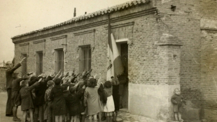 Niños cantando el 'Cara al sol'; otro se oculta tras la pared