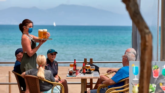 Una camarera sirve unas bebidas en una terraza de L'Escala (Girona) Una camarera sirve unas bebidas en una terraza de L'Escala (Girona)