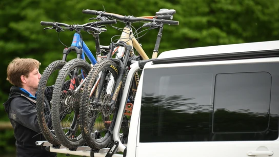 Un hombre carga unas bicicletas en su vehículo Un hombre carga unas bicicletas en su vehículo