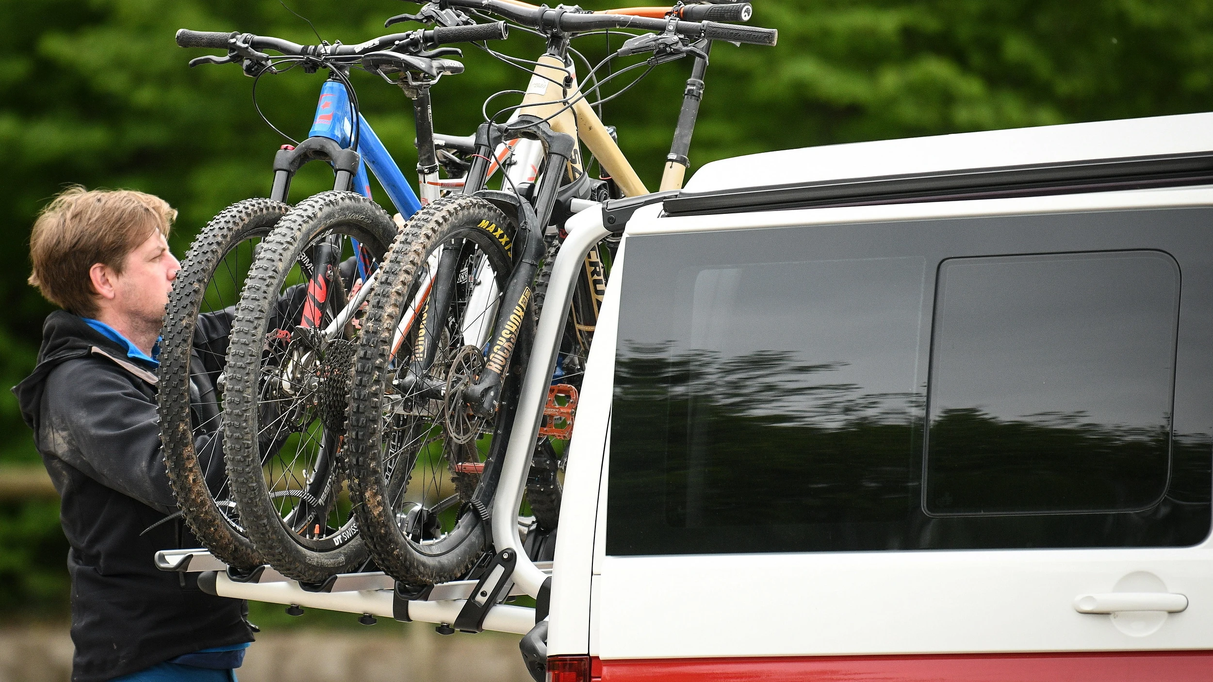 Un hombre carga unas bicicletas en su vehículo