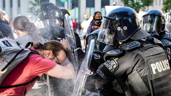 Los agentes rocían pimienta a un manifestante mientras lo empujan hacia atrás Los agentes rocían pimienta a un manifestante mientras lo empujan hacia atrás
