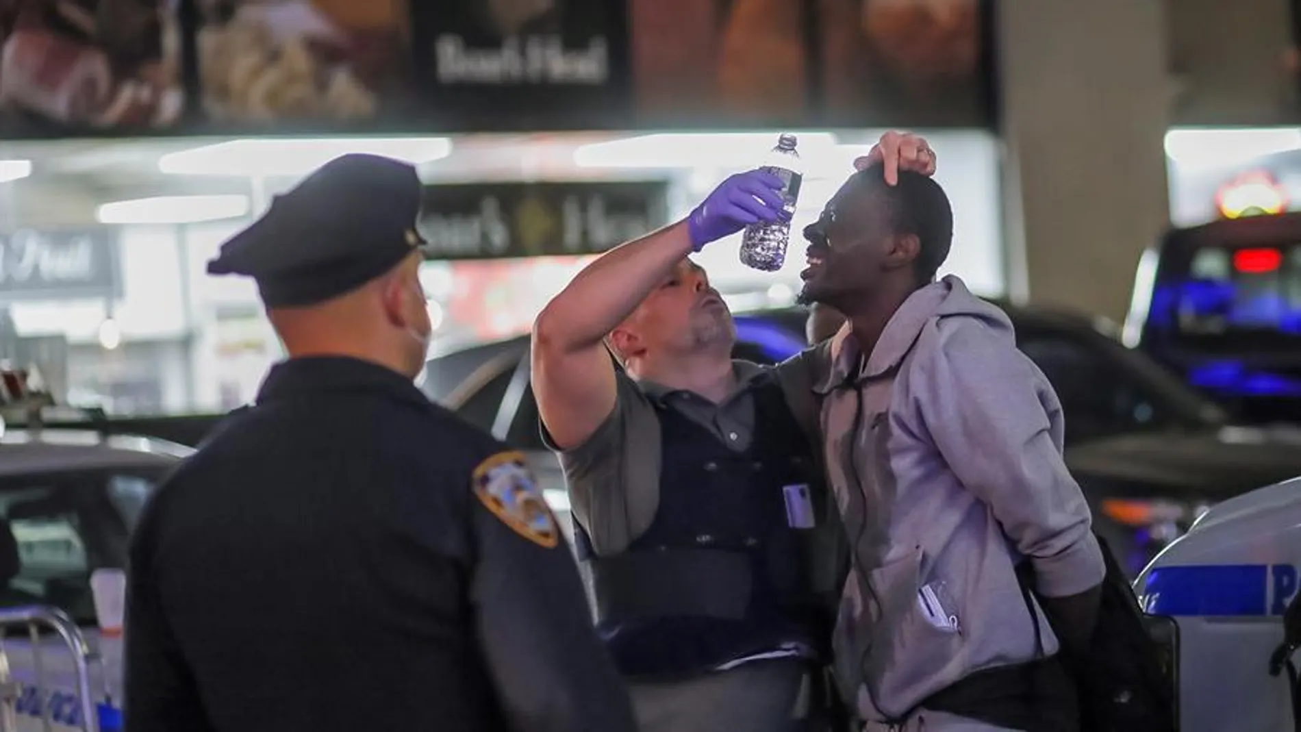 Oficiales del Departamento de Policía de Nueva York prestan ayuda a un detenido