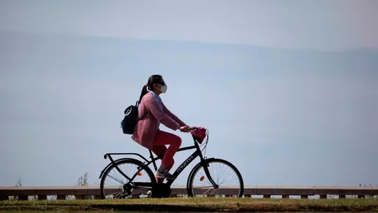 Una mujer con mascarilla pasea en bicicleta durante la desescalada Una mujer con mascarilla pasea en bicicleta durante la desescalada
