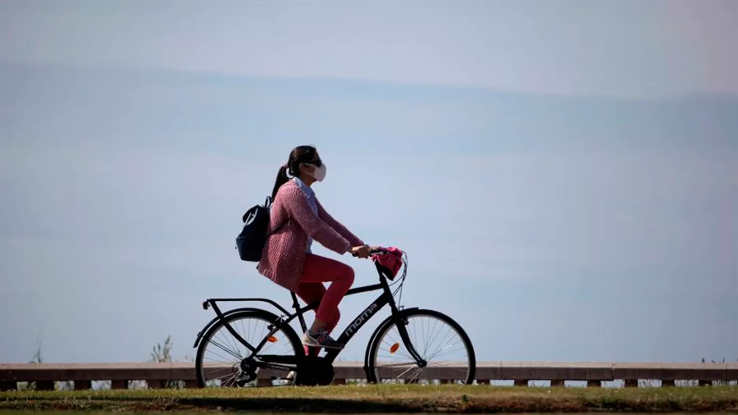 Una mujer con mascarilla pasea en bicicleta durante la desescalada Una mujer con mascarilla pasea en bicicleta durante la desescalada
