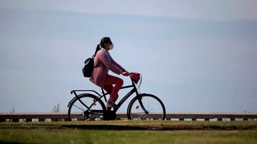 Una mujer con mascarilla pasea en bicicleta durante la desescalada