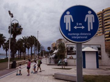Una familia en el paseo marítimo de la Malagueta ante un disco que recuerda mantener la distancia de 2 metros entre personas Una familia en el paseo marítimo de la Malagueta ante un disco que recuerda mantener la distancia de 2 metros entre personas