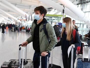 Pasajeros con mascarilla en un aeropuerto Pasajeros con mascarilla en un aeropuerto