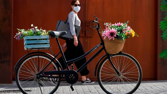 Una mujer con mascarilla pasa junto a una bicicleta aparcada en una calle de Ávila Desescalada