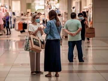Personas con mascarilla compran en un centro comercial Personas con mascarilla compran en un centro comercial