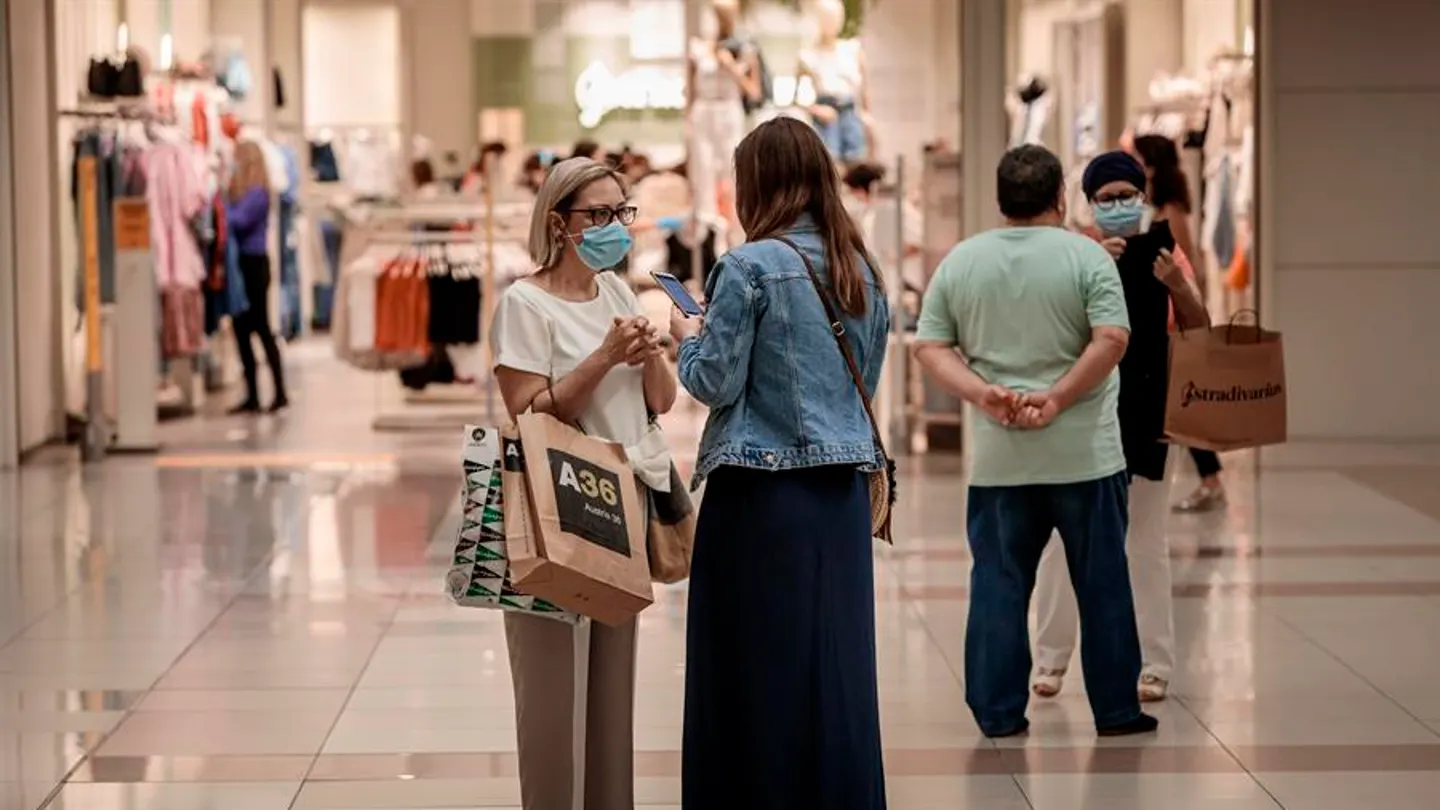 Varias personas realizan compras en un centro comercial con mascarillas. Varias personas realizan compras en un centro comercial con mascarillas.