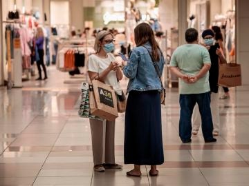 Varias personas realizan compras en un centro comercial con mascarillas. Varias personas realizan compras en un centro comercial con mascarillas.
