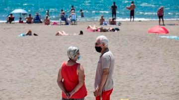 Personas con mascarilla en una playa