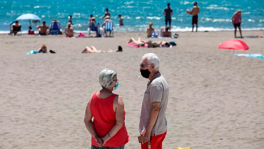 Personas con mascarilla en una playa (Archivo)