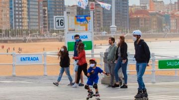 Un grupo de personas pasean por el paseo marítimo de la playa de San Lorenzo de Gijón .