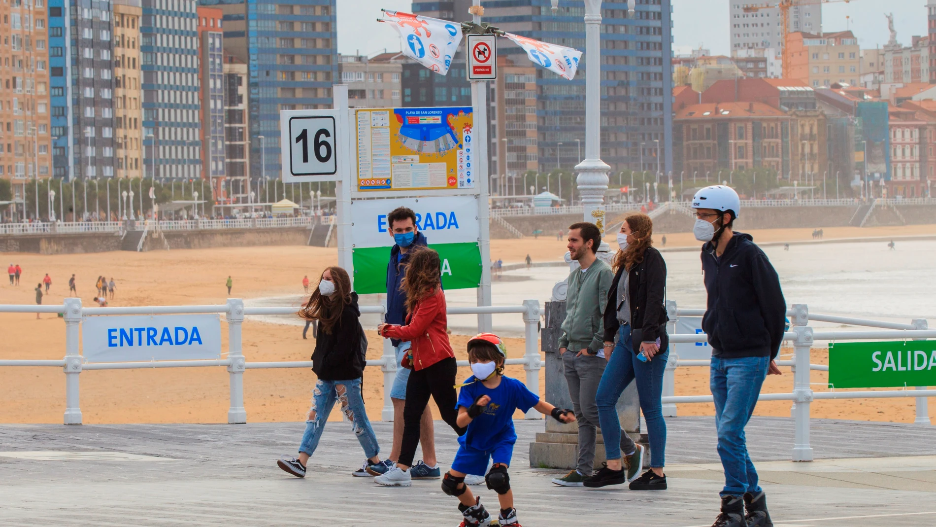 Un grupo de personas pasean por el paseo marítimo de la playa de San Lorenzo de Gijón .