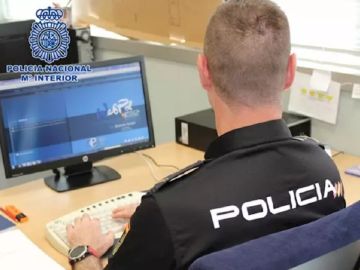 Imagen de archivo de un policía frente a un ordenador Imagen de archivo de un policía frente a un ordenador