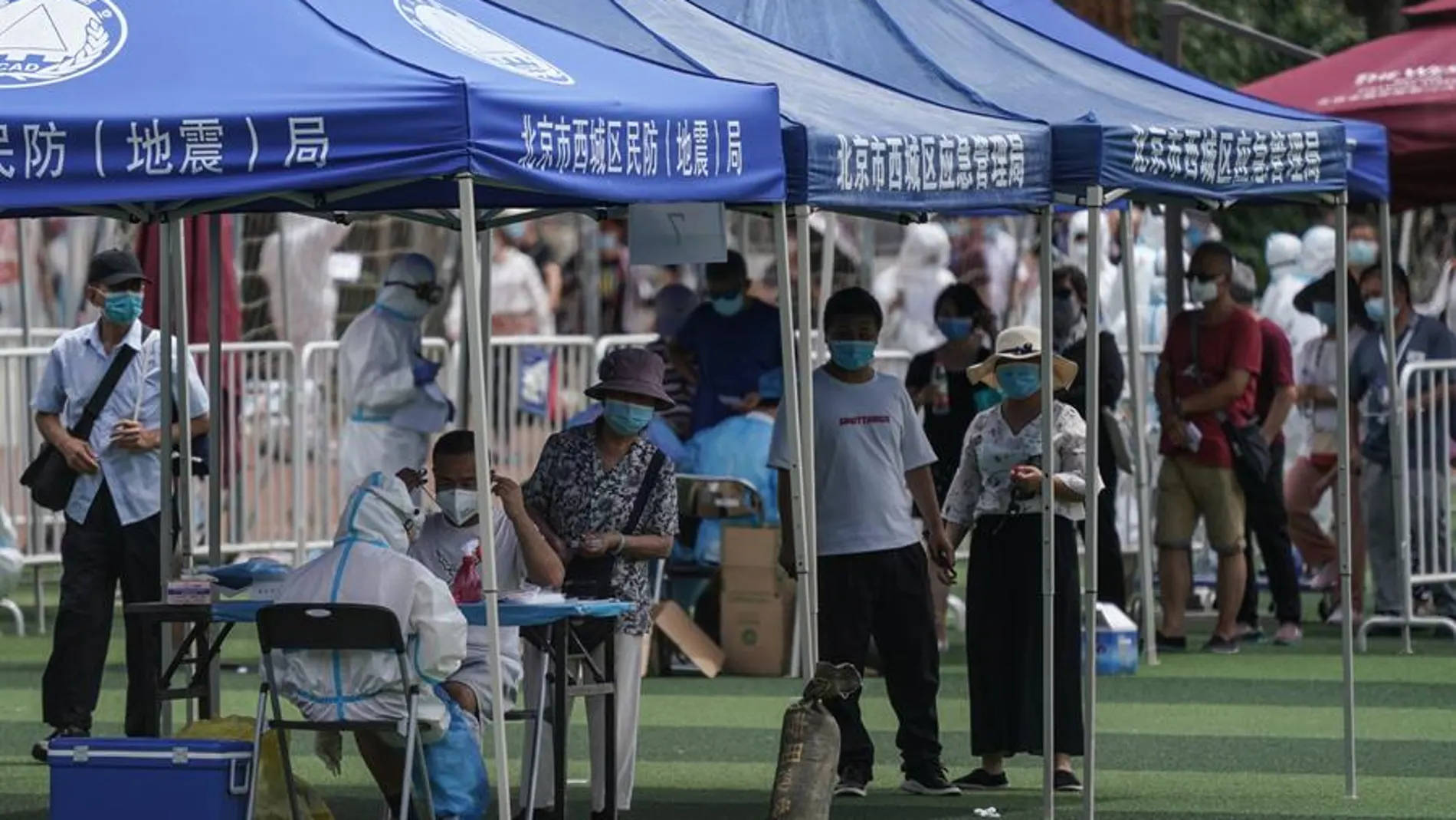 Residentes o gente que visitó el mercado de Xinfadi hacen cola para hacerse el test de coronavirus en el pabellón deportivo de Guang'an en Pekín.