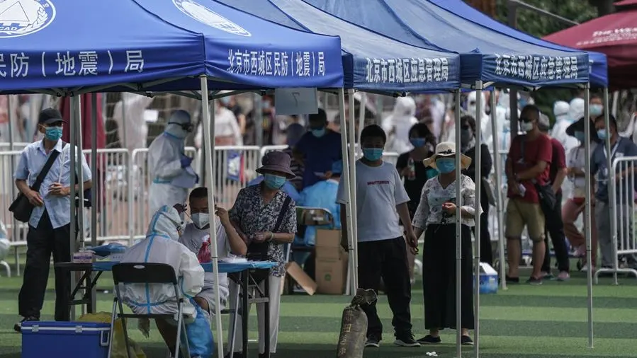 Residentes o gente que visitó el mercado de Xinfadi hacen cola para hacerse el test de coronavirus en el pabellón deportivo de Guang'an en Pekín.