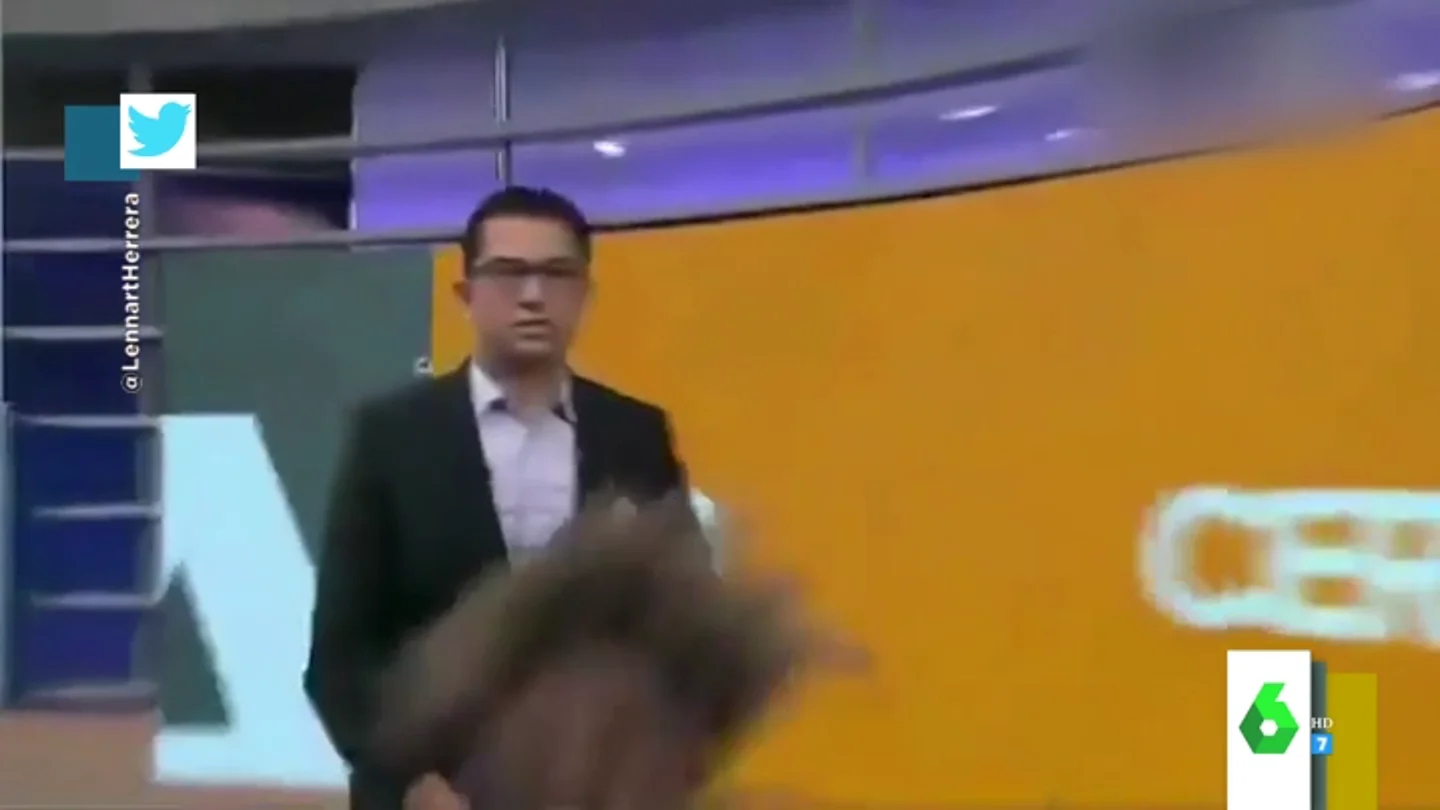La reacción de un presentador cuando su compañera se se cae delante de él en pleno directo La reacción de un presentador cuando su compañera se se cae delante de él en pleno directo