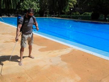 Un operario desinfecta el perímetro de una piscina. Un operario desinfecta el perímetro de una piscina.
