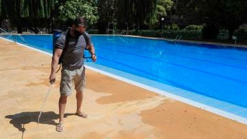 Un operario desinfecta el perímetro de una piscina.